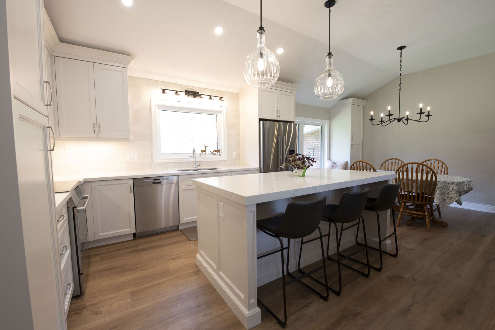 White kitchen with large quartz island and glass pendants